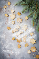 Homemade shortbread star shape sugar with sugar powder and  branch of fit-tree on thread over blue texture surface. Selektive focus.  Christmas or New Year background.  Top view with space.