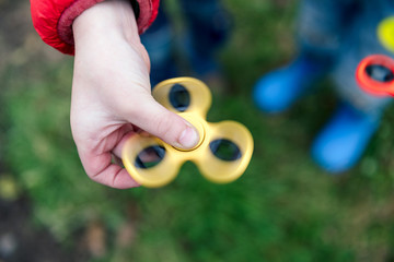 Two boys playing fidget spinners. Outdoor.
