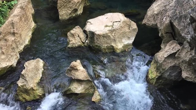 The water of this crystal clear creek is flowing down many small romantic cascades on limestone rock-reefs.
