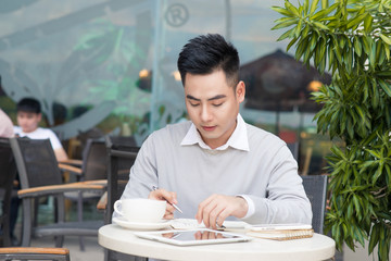 Young asian businessman working with documents at cafe.