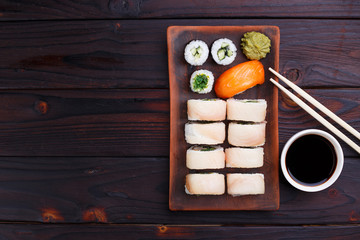Appetizing sushi set with grouper, chuka and salmon served on clay plates with soy sauce and chopsticks, top view, copy space. Delicious Japanese food, tasty seafood, sushi restaurant concept