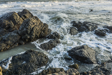 Waves crashing over black rocks on the sea shore. Vung Tau, Vietnam.
