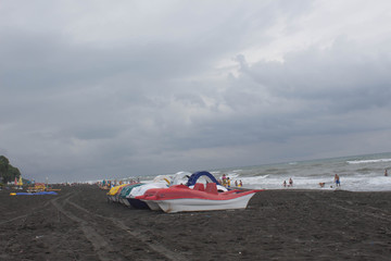colorful pedalo paddle boats on the beach, overcast, clouds, waves