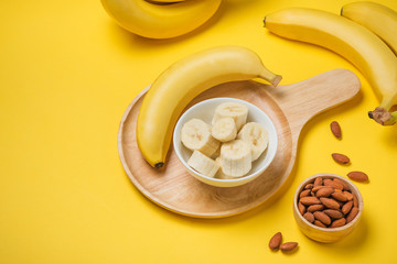 A banch of bananas with almonds on yellow background. © makistock