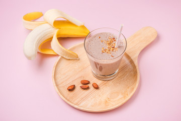 Fresh made banana smoothie in a glass on pink background