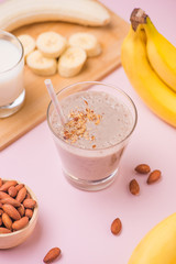 Fresh made banana smoothie in a glass on pink background