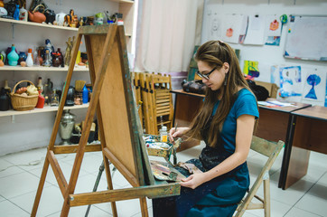 Pretty Girl artist paints on canvas painting on the easel
