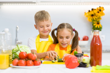 Children cut cucumbers for vegetable salad