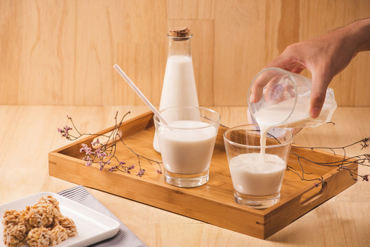 milk pour from bottle, almond candies on wooden background