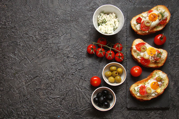 Bruschetta, crostini with cream cheese, with cherry tomatoes, herbs, olives, capers and fried egg