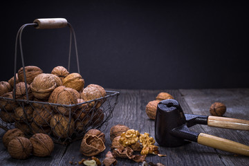 walnuts in basket with nutcracker, wooden background horizontal
