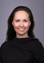 Fototapeta premium Natural portrait of young woman in black on a dark gray background. The woman smiles