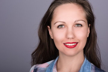 Closeup portrait of a beautiful young woman with flowing hair and red lipstick on a neutral gray background