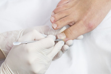 Female foot in the process of pedicure procedure in a beauty salon close-up.