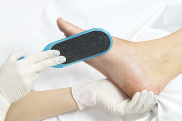 Female foot in the process of pedicure procedure in a beauty salon close-up.