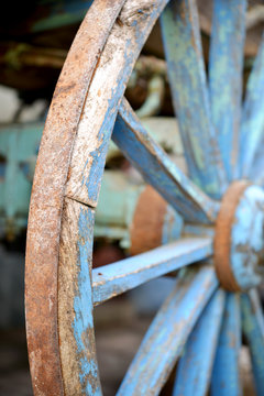 Close-up of an old blue wooden cart wheel with rusty iron rim in a vintage rustic style.