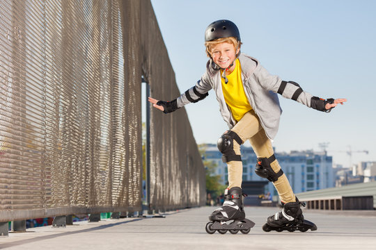 Happy boy on rollers making trick at skate park