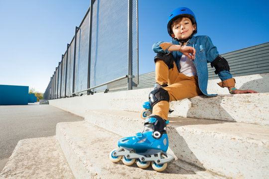 Boy wearing roller blades sitting on the stairs