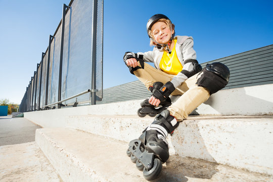 Smiling boy in roller blades sitting on the stairs