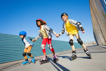 Fototapeta na wymiar Kids holding hands while rollerblading outdoors