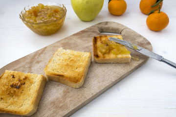 A sandwich with fruit jam and a knife that spread the jam on fried bread.