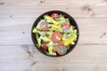 Appetizing vegetable salad consisting of tomatoes, avocado, yellow sweet pepper, lettuce and seasonings.