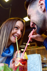 Young Love Couple in Café Drinking from the same Glass with Straws