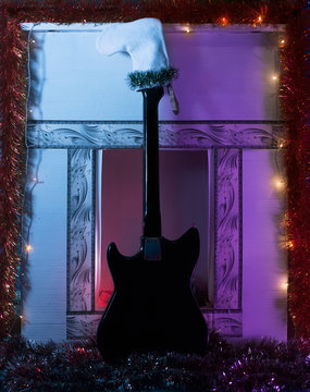 Black guitar is in a white stocking against the fireplace.