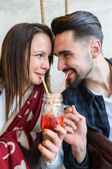 Young Love Couple in Café Drinking from the same Glass with Straws