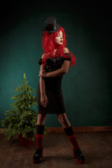 portrait of a teenage girl in a black dress with a red wig and in a carnival hat. Christmas new year