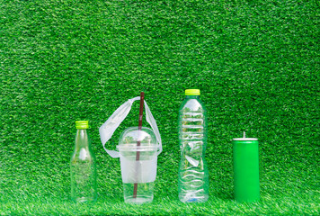 Hand hold show Recyclable plastic bottle a glass of water green background