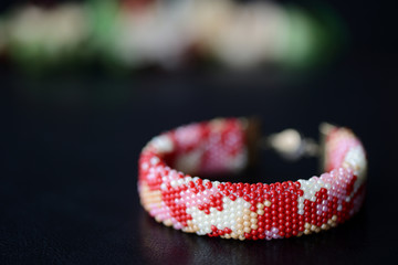 Red camouflage seed beads bracelet on a dark background close up