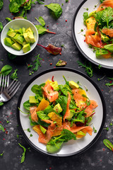 Fresh salmon salad with avocado, orange and green vegetables.