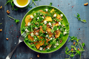 Fresh Tasty Persimmon salad with arugula, nuts, feta cheese, olive oil and herbs. healthy food