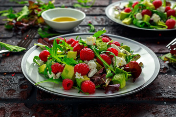 Fresh Tasty Raspberry salad with avocado, green vegetables, nuts, feta cheese, olive oil and herbs. healthy food.