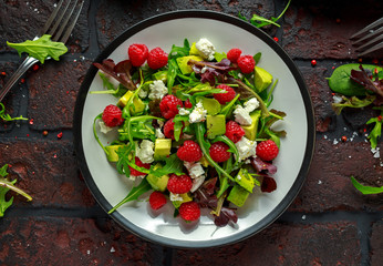 Fresh Tasty Raspberry salad with avocado, green vegetables, nuts, feta cheese, olive oil and herbs. healthy food.