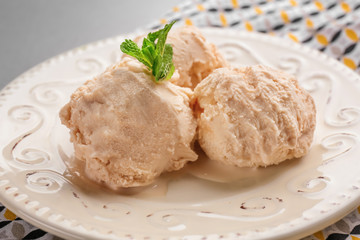 Plate with caramel ice cream on table, closeup
