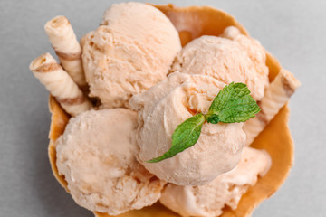 Waffle bowl with caramel ice cream on grey background, closeup