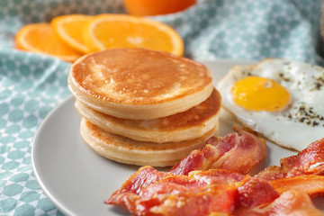 Plate with yummy pancakes, fried bacon and egg on table