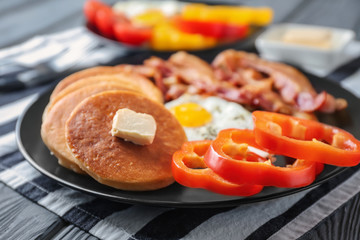 Plate with yummy pancakes, pepper, fried egg and bacon on table