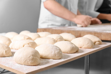 Raw loaves of bread on table in bakery