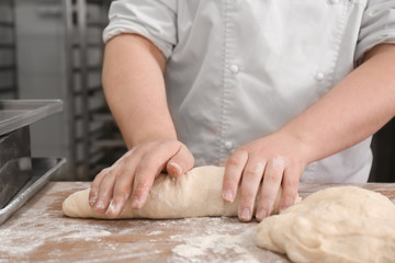 Obraz na płótnie Canvas Man preparing bread on table in bakery