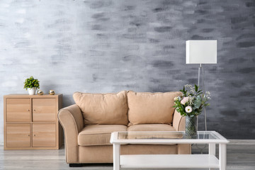 Stylish sofa with white table in interior of living room