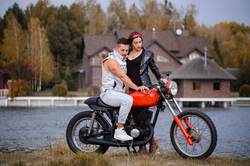 Obraz na płótnie Canvas stylish and trendy couple in love on a motorcycle flirting close-up on a background of late autumn in the park