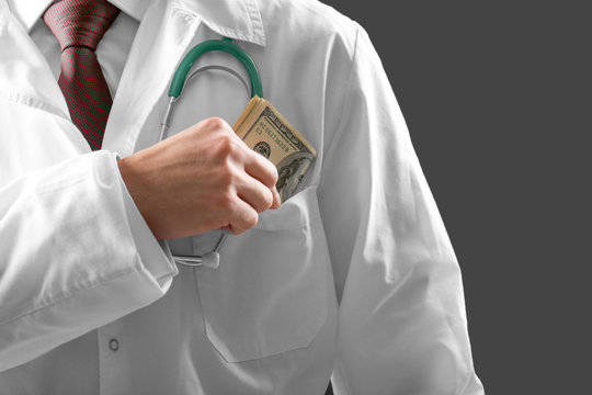 Doctor putting money in pocket on grey background, closeup