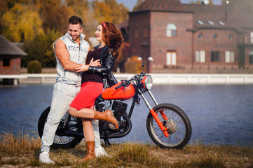 Fototapeta na wymiar stylish and trendy couple in love on a motorcycle flirting close-up on a background of late autumn in the park