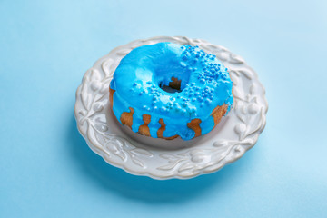 Plate with blue donut on color background
