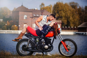 stylish and trendy couple in love on a lying motorcycle flirting close-up on a background of late autumn in the park