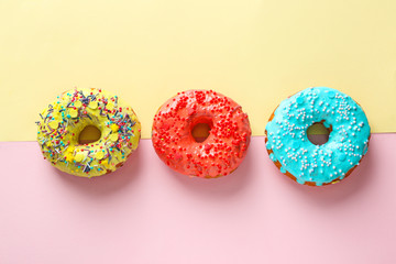 Tasty donuts with sprinkles on color background