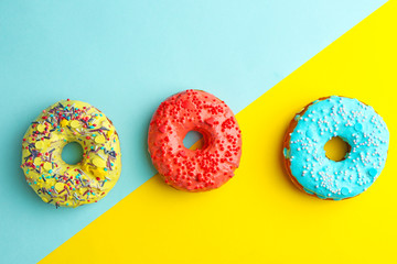 Tasty donuts with sprinkles on color background